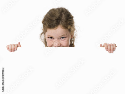 Young girl peeking over white sign