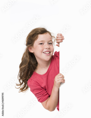 Pretty, young girl, smiling, looking around large white sign