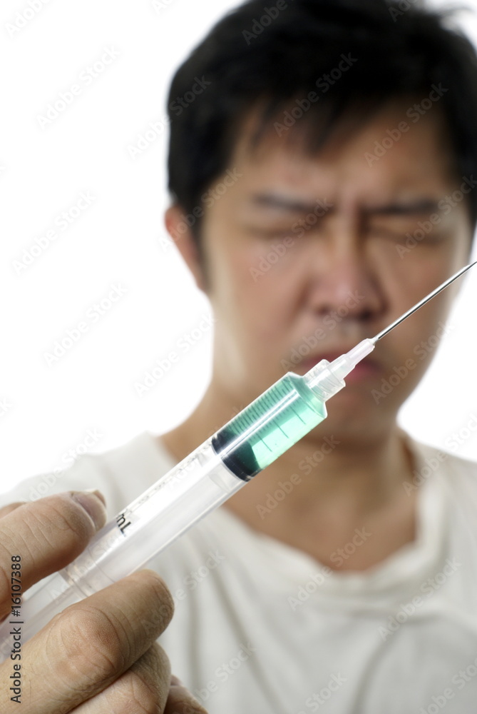 Asian man holding syringe with green liquid Asian man holding syringe with green liquid