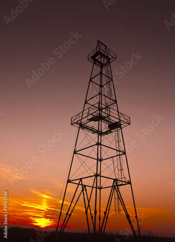 Abandoned oil well profiled on warm sunset