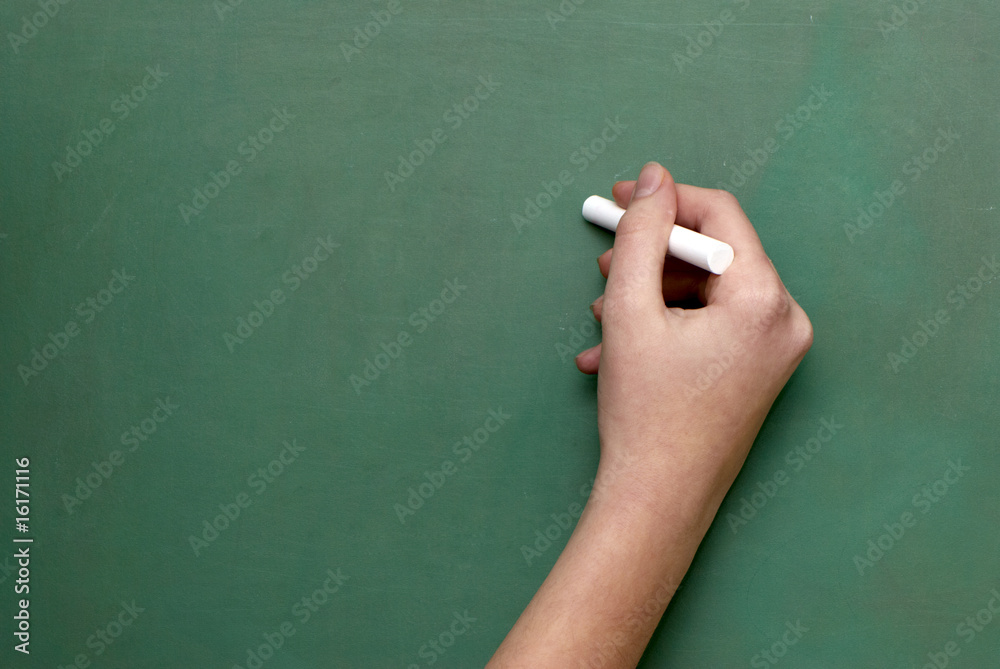 A man holds a piece of chalk, as if ready to write on a chalkboa A man holds a piece of chalk, as if ready to write on a chalkboa