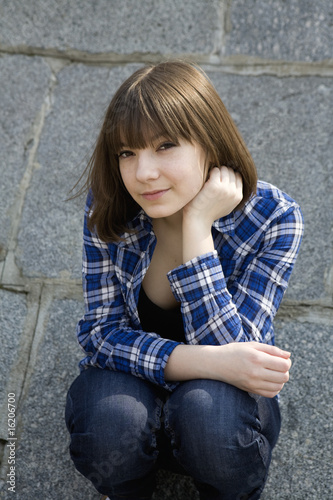 portrait of young teen girl sitting  at stone wall © elenarostunova