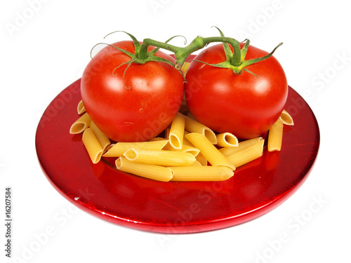 tomatoes with uncooked pasta served on red plate