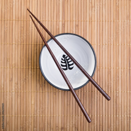 Chopsticks with  ceramic bowl on bamboo mat