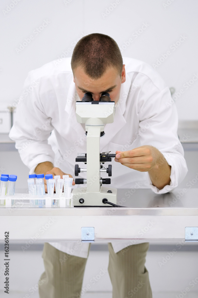 Young doctor watching samples through microscope. Stock Photo | Adobe Stock