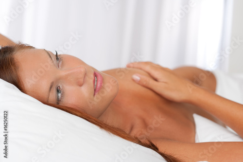 Naked woman lying in white bed