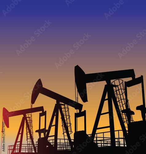 Three oil wells in the desert at dusk