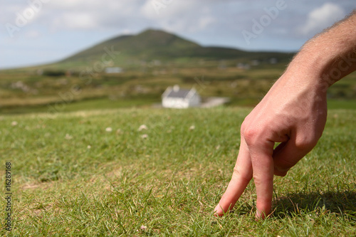 Two fingers on grass. A house on a background.