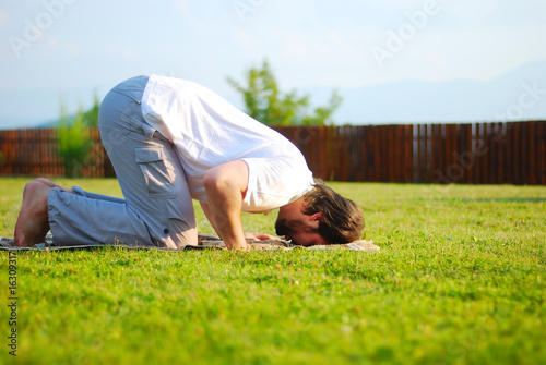 Canvas Print Young attractive man on green meadow praying