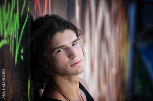 young man in front of graffitti wall