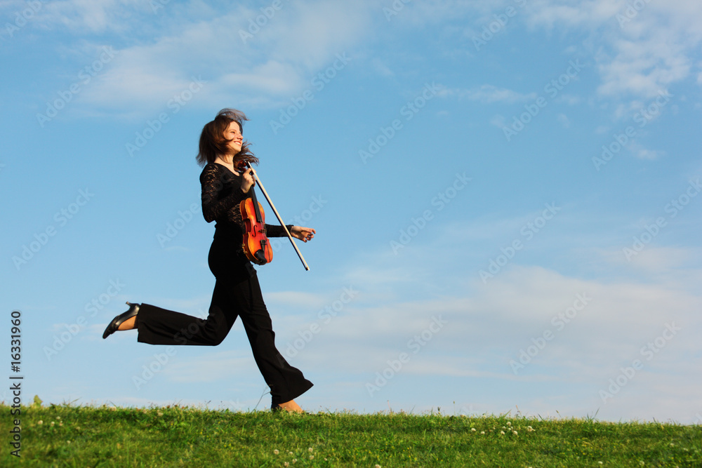 girl with violin runs on grass against sky, side view girl with violin runs on grass against sky, side view