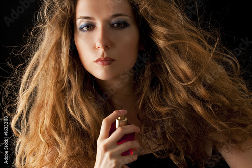 attractive blond woman applying perfume on her body