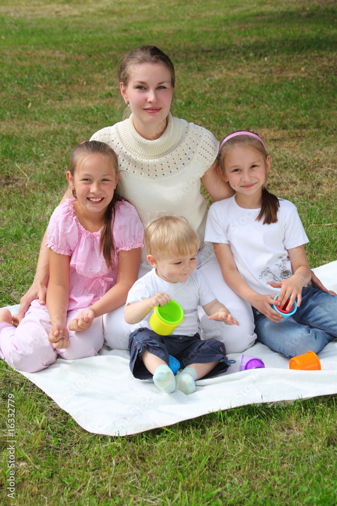 Mother with children sits on laying on grass Mother with children sits on laying on grass