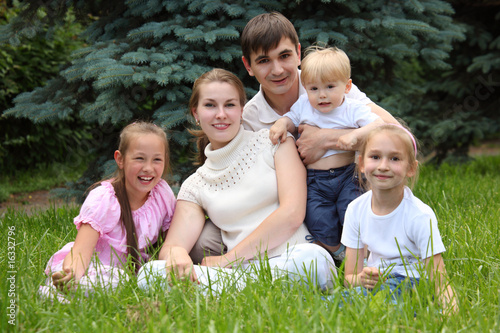 family of five outdoor in summer sit on grass
