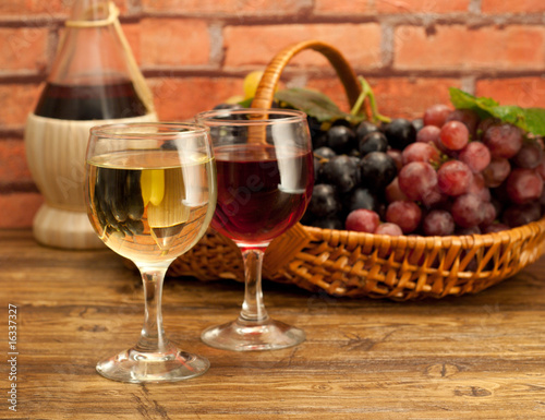 Two glasses of wine and grapes in a basket.