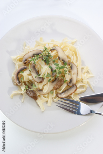 Pasta with mushroom and herbs on a white plate