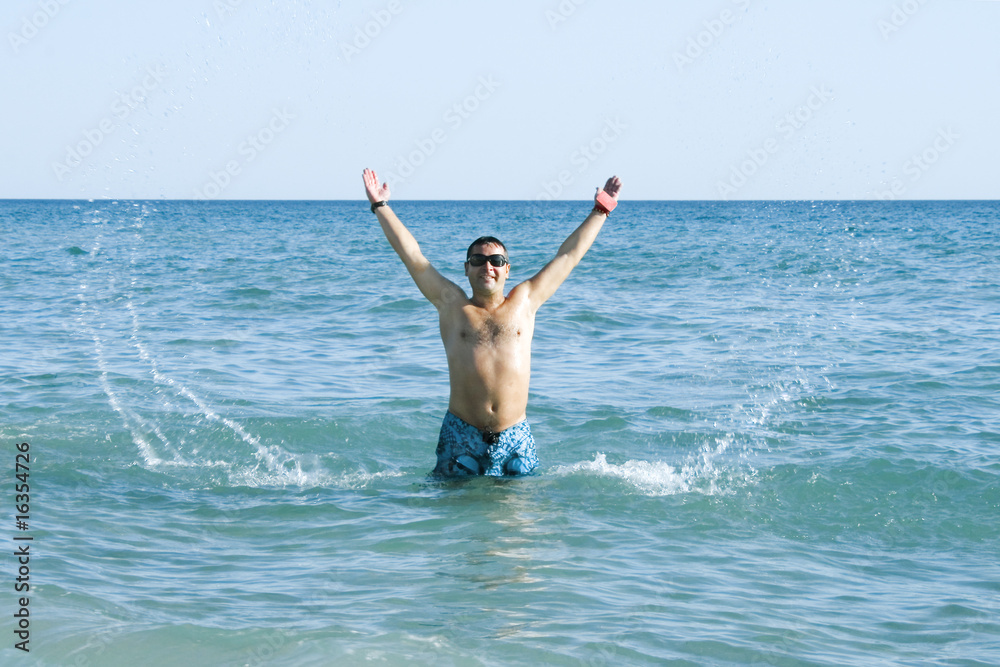 tanned man jumping out of the sea with splash