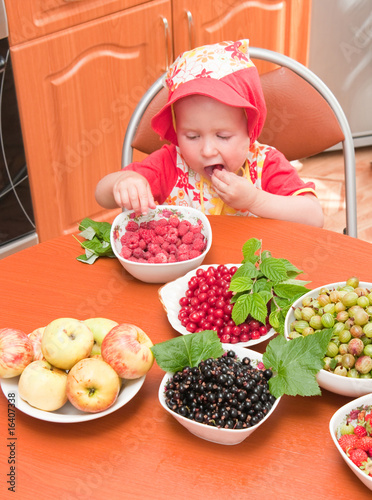 The little girl eats a berry
