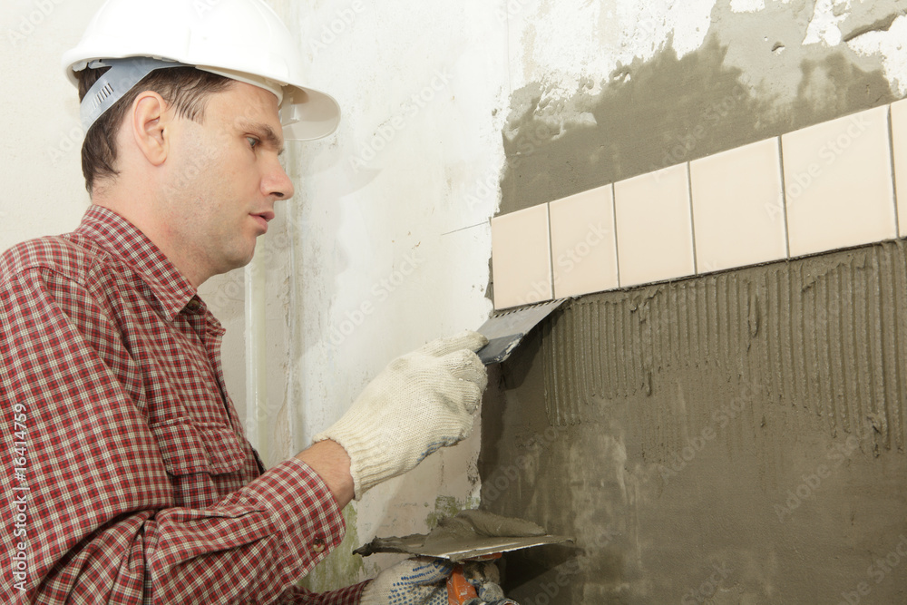 Man installs ceramic tile on a wall