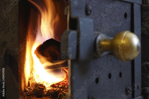 Fuoco che brucia all'interno di stufa a legna. Stufa tradizionale con tronchi sul fuoco, riscaldamento tradizionale photo