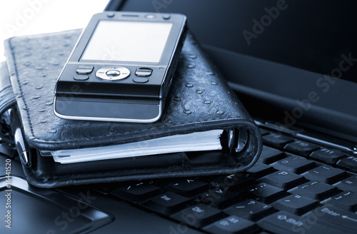 Organizer and mobile phone laying on laptop