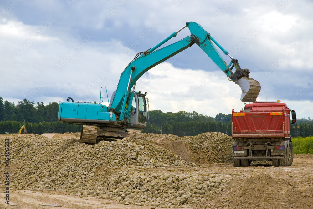 Fototapeta premium Excavator loading sand or rocks in lorry