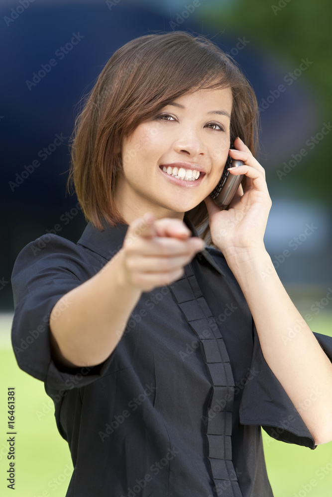 Beautiful Oriental Woman on Her Smart Cell Phone and Pointing Beautiful Oriental Woman on Her Smart Cell Phone and Pointing