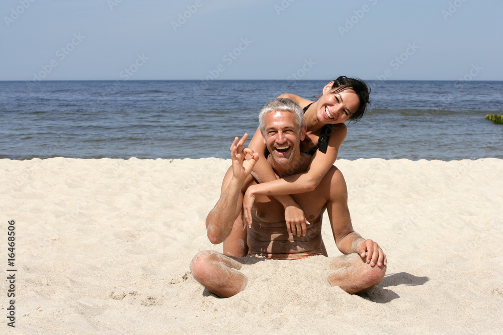 Attractive couple sitting on the beach. Man indicated OK sign. Attractive couple sitting on the beach. Man indicated OK sign.