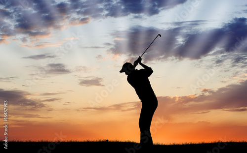 Silhouette of golfer mid-swing photo