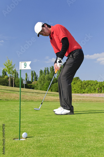 Junge Golfer putten auf dem Green photo