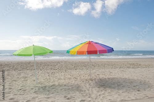 Colorful umbrellas on the beach waiting to be claimed. © dmvphotos