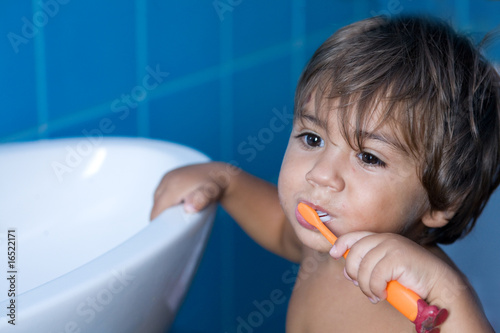 bambino che si lava i denti con lo spazzolino photo