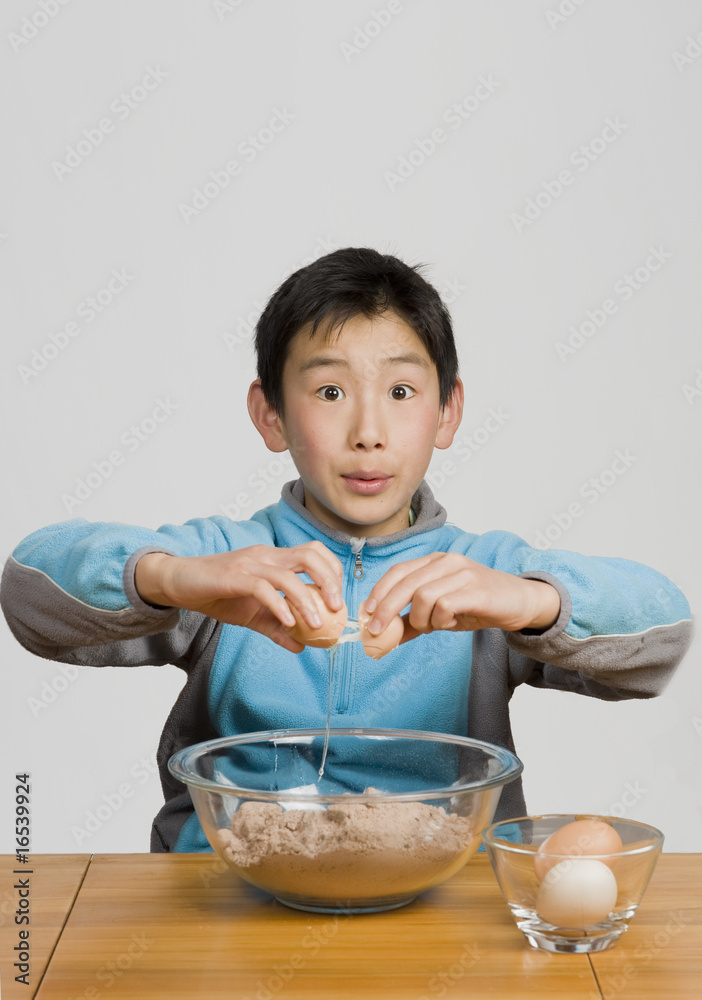 young boy cracking egg into bowl young boy cracking egg into bowl