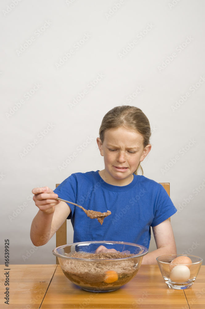 young girl making funny face while mixing cake batter young girl making funny face while mixing cake batter
