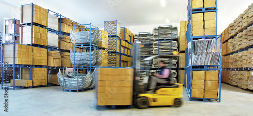 Automotive parts shipping warehouse. A moving forklift moves boxes inside the warehouse photo