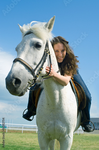 smiling girl embraces a white horse