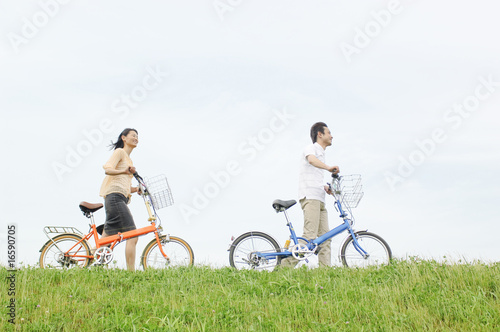 自転車を押して丘の上を歩くカップル photo