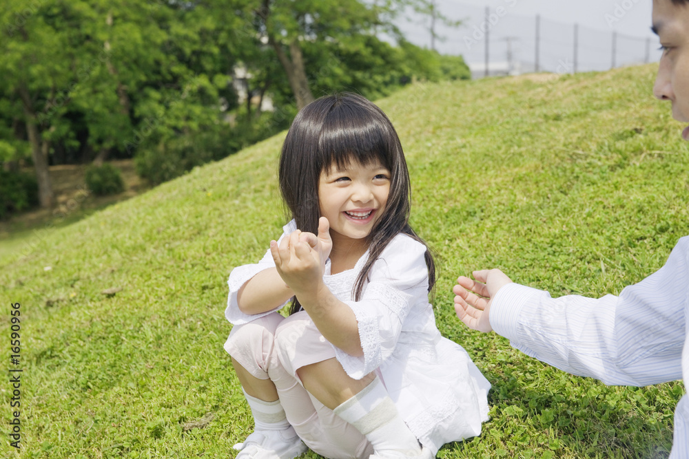 公園で娘の手をとろうとする父親