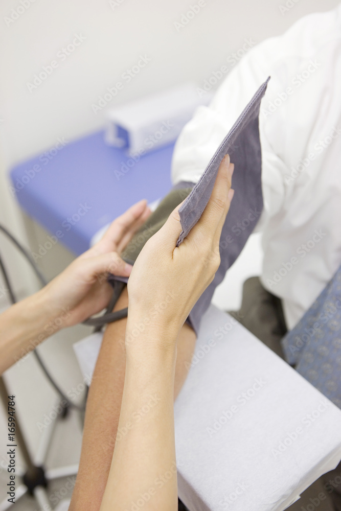 血圧計を男性患者の腕に取り付ける看護師の手