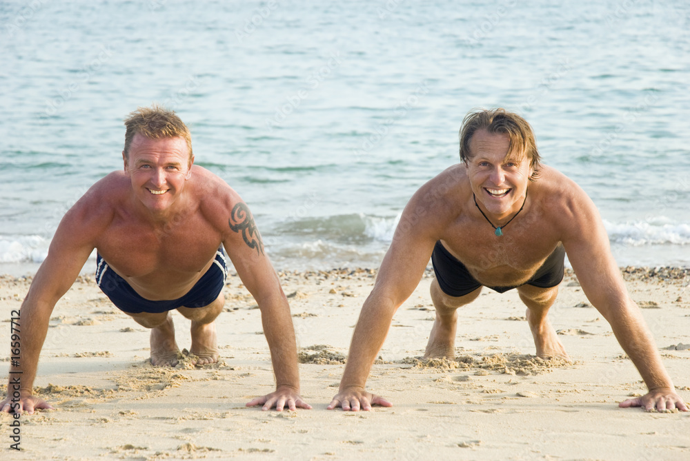 Two happy smiling men exercising on the beach. Two happy smiling men exercising on the beach.