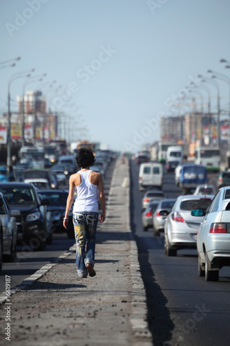 girl goes on highway middle in city, view from back © Pavel Losevsky