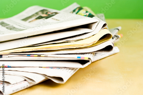 Stack of newspapers lying on the table on green background