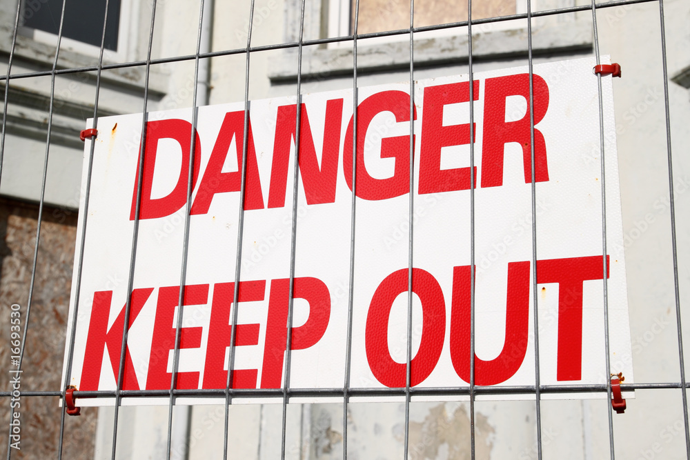 Obraz premium Danger keep out sign on a wire security fence.