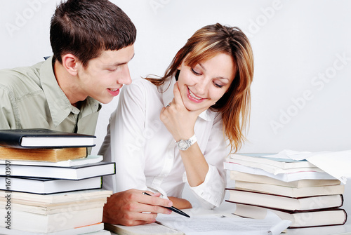 Young female and male models sitting on desk with many books photo