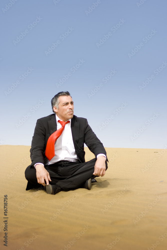 A business man relaxing and sit down on the sand of the desert A business man relaxing and sit down on the sand of the desert