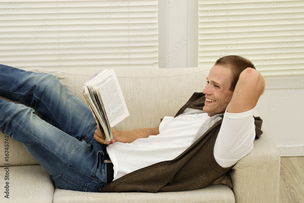 jeune homme lisant un livre sur un sofa