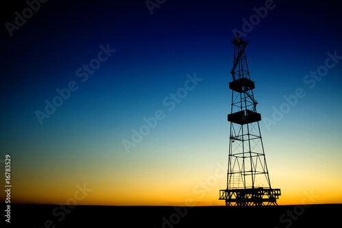 Oil rig silhouette over blue sky