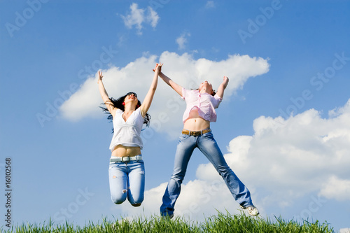 two happy women jumping on the green grass