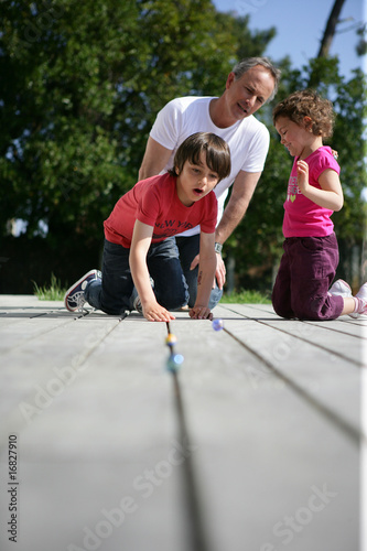 Homme jouant aux billes avec un petit garçon et une petite fille
