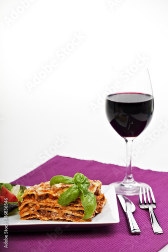 Lasagne al Forno auf einem Teller mit Rotwein